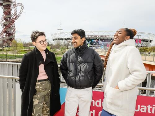 Three young people laughing outside of London Stadium