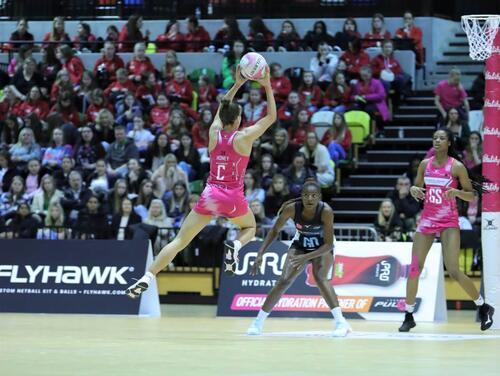 A Netball player jumping to shoot a goal during a game 