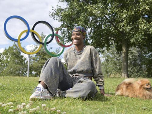 A person and dog pose in front of the Olympic Rings 