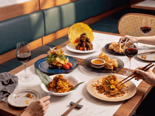 People using chopsticks to eat dishes on a restaurant table