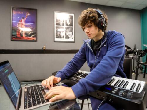 Someone uses a laptop with a mixing desk at East Summer School
