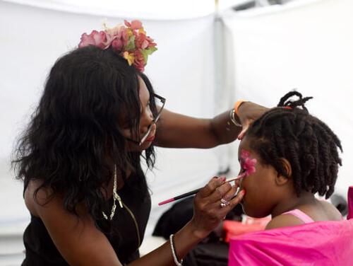 A child has their face painted by an adult Great Get Together