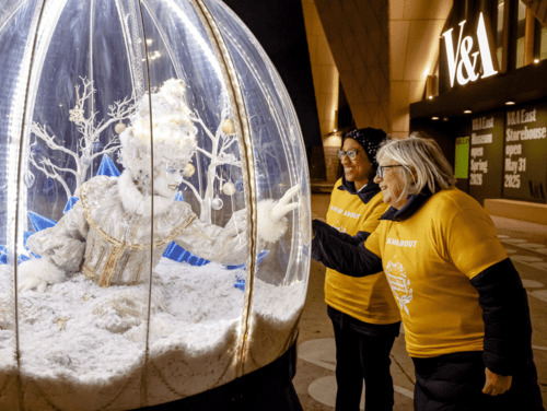 Two volunteers interacting with christmas performer 