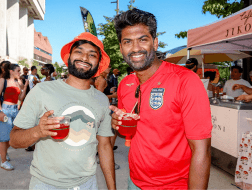 Two men pose for camera with drinks in their hands