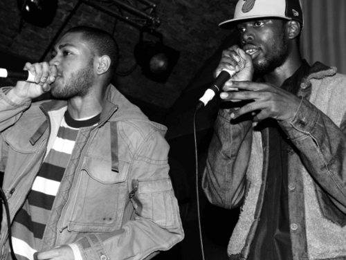 A black and white image of Kano and Ghetts performing