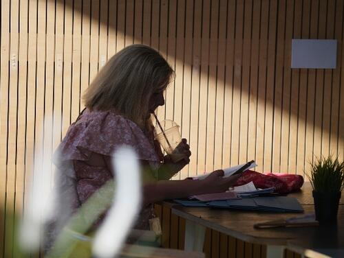 Woman drinking coffee and working inside Timber Lodge cafe