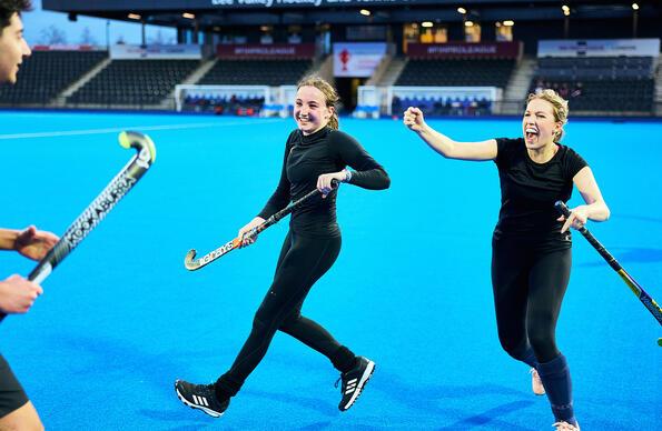 Three young adults playing Hockey on blue courts