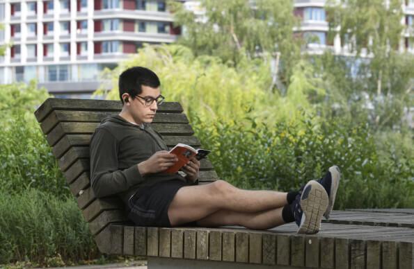A man sits on a bench reading a book
