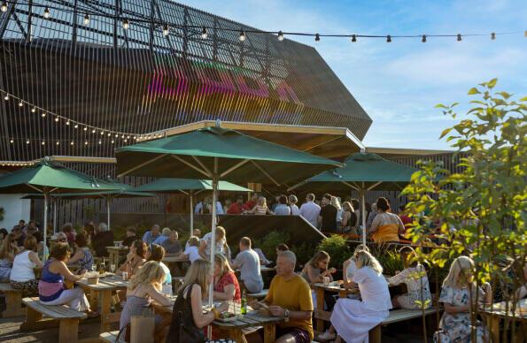 Tables of people sit outside ABBA Voyage enjoying a pre show drink