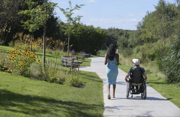 One person walking and another in a wheelchair go through the London Blossom Garden