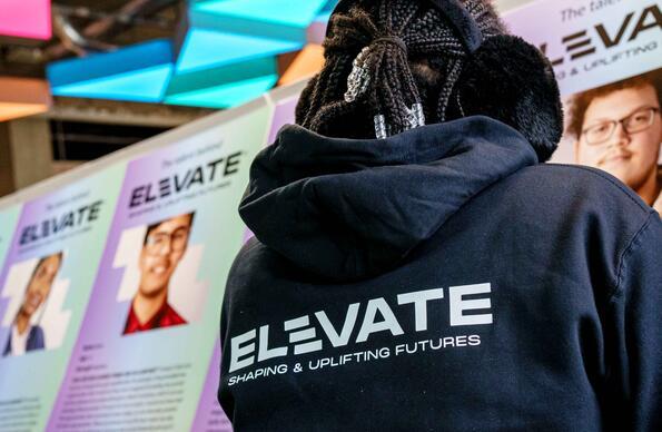 Person looking at headshots wearing a hoodie that reads Elevate