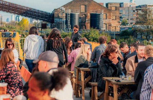 Groups of people sitting outside Hackney Bridge in the sun