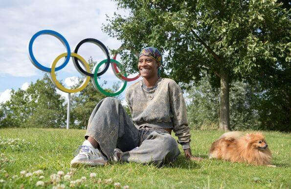 Man sitting with dog in front of the Olympic Logo