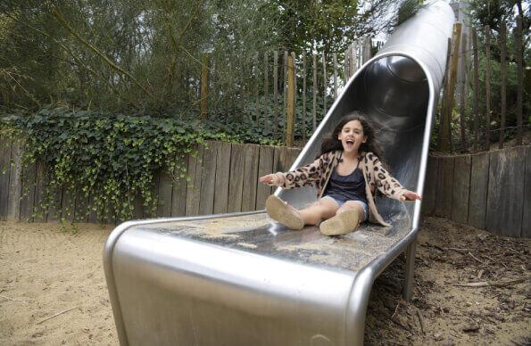 A girl slides down a slide at Tumbling Bay Playground A girl slides down a slide at Tumbling Bay Playground