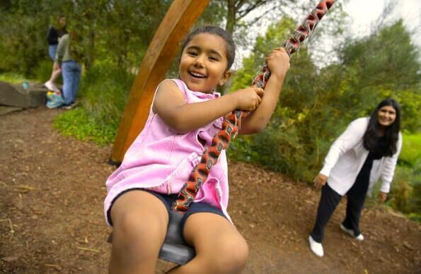 A child swings on a rope swing at tumbling bay playground