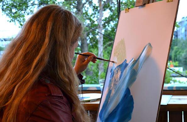 A person paints a blue picture at a workshop at Barge East A person paints a blue picture at a workshop at Barge East