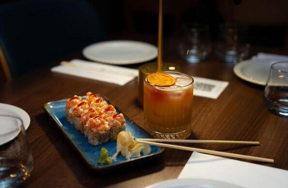 A sushi platter next to a small orange cocktail