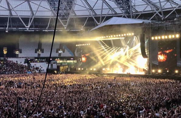 A large crowd watches a musician at London Stadium