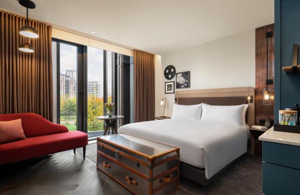 A well-presented hotel room at the Gantry with bed, sofa and view out of the window