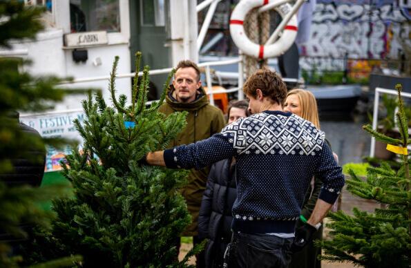 A christmas market at Barge East with a group of people stood buying a christmas tree A christmas market at Barge East with a group of people stood buying a christmas tree