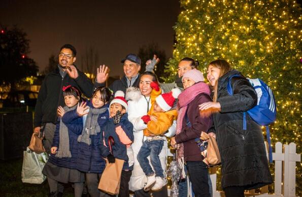 A group of people next to a christmas tree