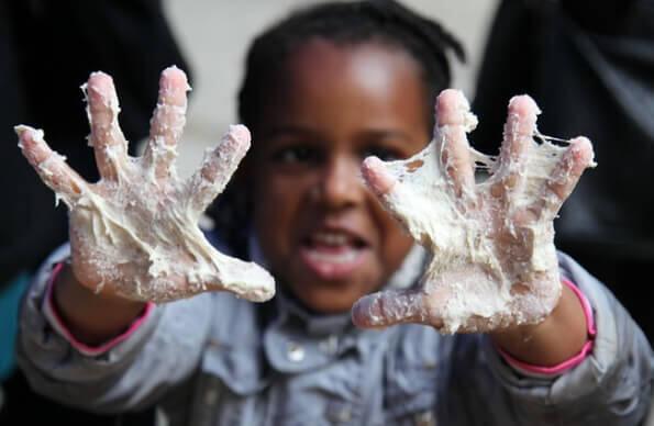 A child holds up their mucky hands A child holds up their mucky hands