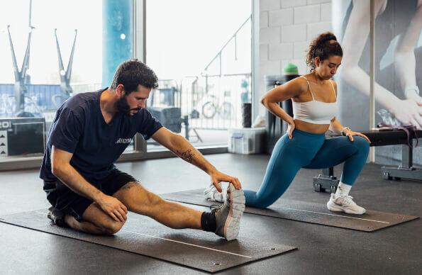 A man and woman stretch in a gym A man and woman stretch in a gym