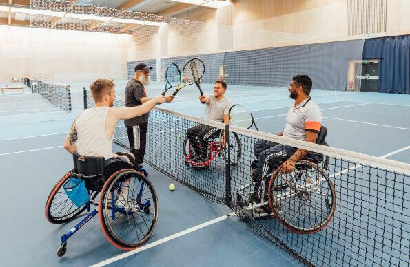 A group of friends in wheelchairs playing tennis A group of friends in wheelchairs playing tennis