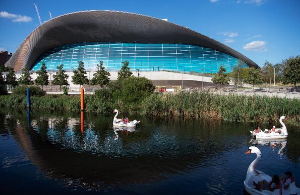 Exterior of London Aquatics Centre surrounded by canal and swan pedalos