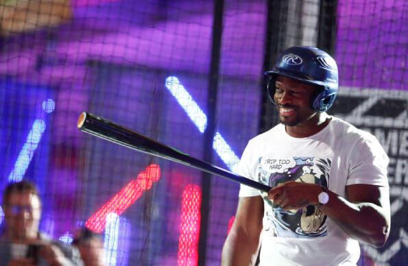 A man smiles in a batting cage holding a bat A man smiles in a batting cage holding a bat