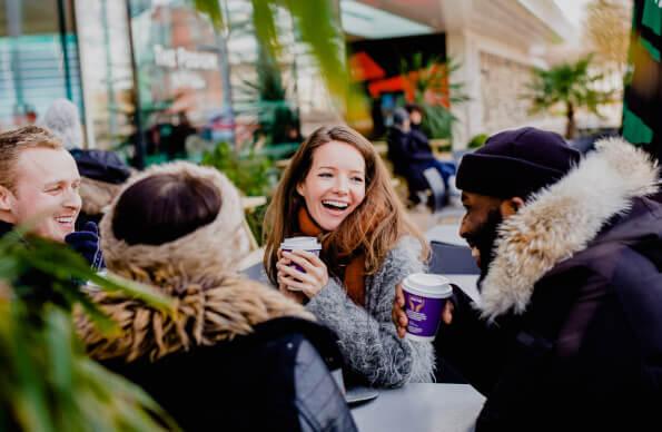 four people sit in winter clothes drinking coffee