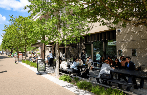 People eating al fresco at retail units on Queen Elizabeth Olympic Park
