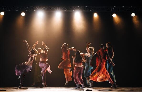 Dancers performing on stage in multicoloured costumes