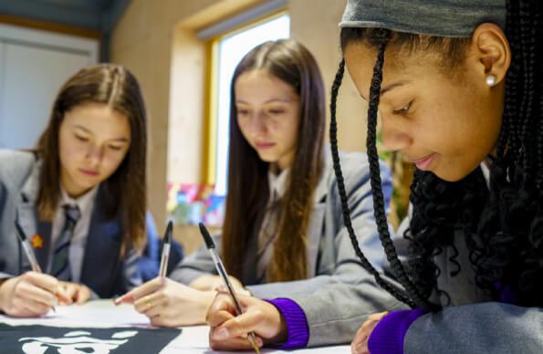 Three schoolkids writing on paper