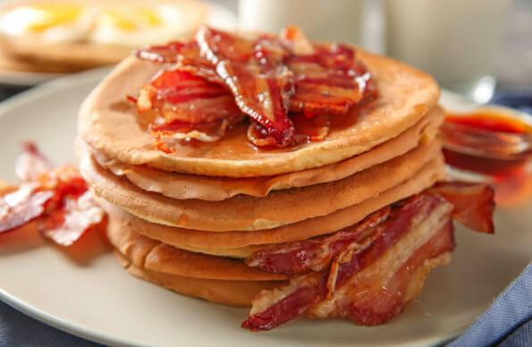 A stack of pancakes with bacon