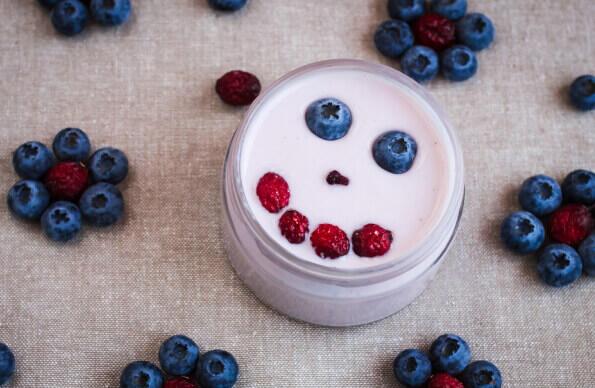 A yoghurt pot with a smile made from berries in it