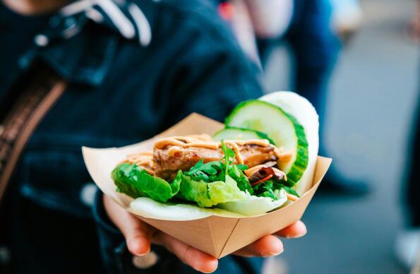 A box of street food with salad is held up to the camera