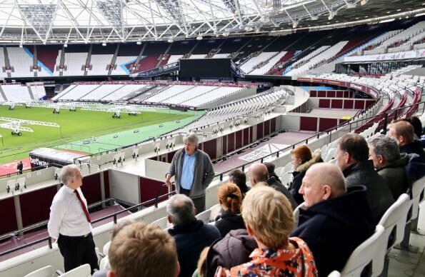 A tour group sits in the stands at London Stadium