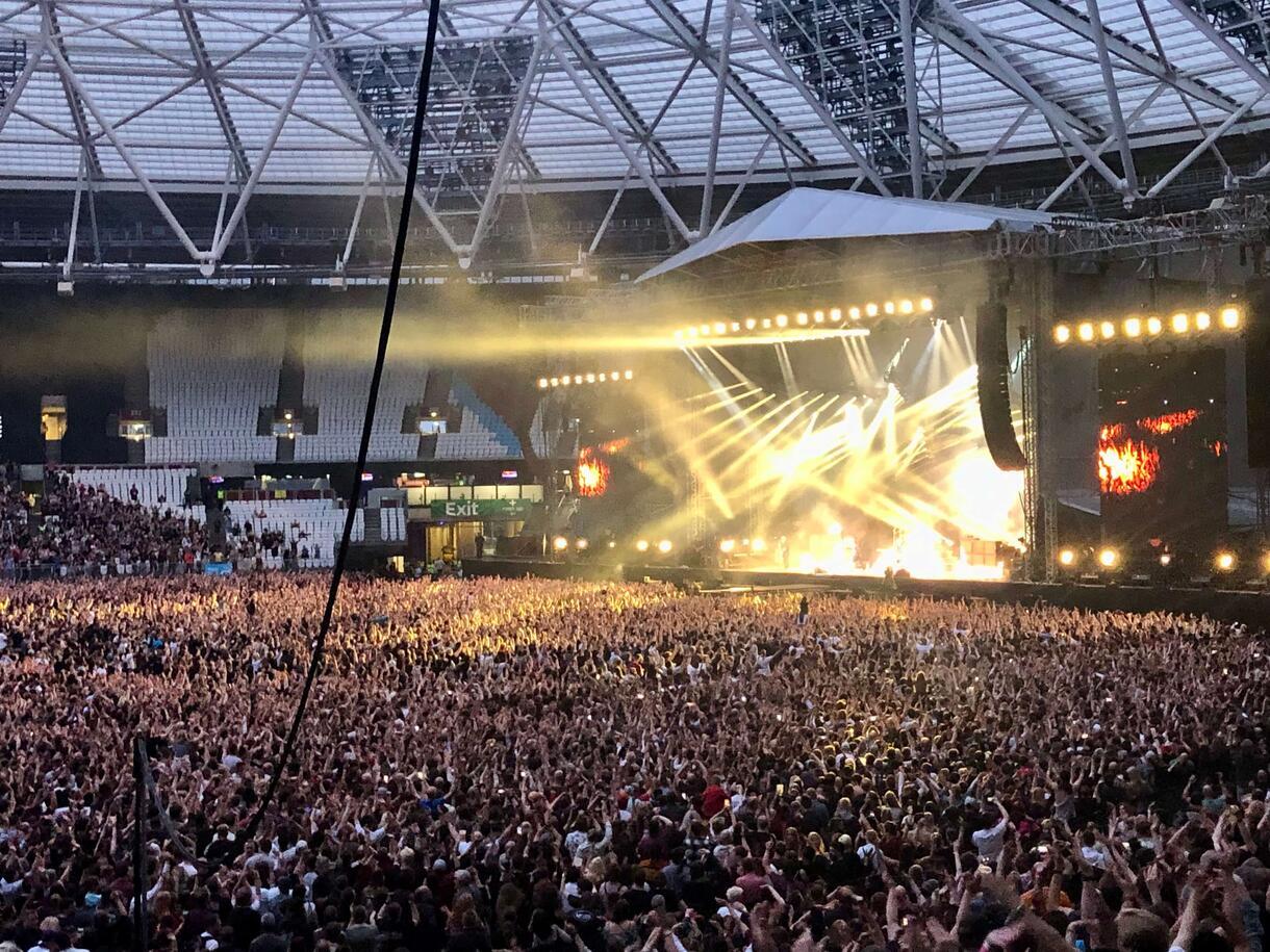 A band plays at London Stadium with lights and a crowd