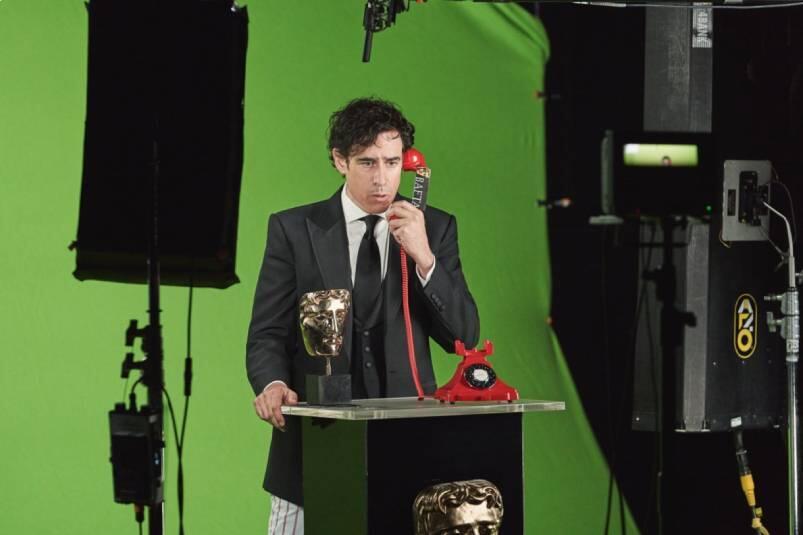 A man answering a telephone with a BAFTA and a green screen at 3 Mills Studio