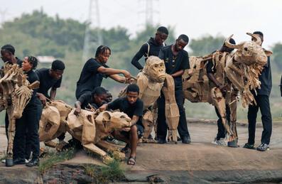 A group of people holding life sized animal puppets