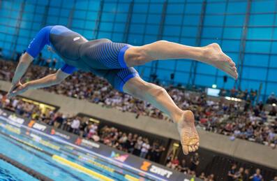 A swimmer dives into the London Aquatics Centre pool competing at supertri