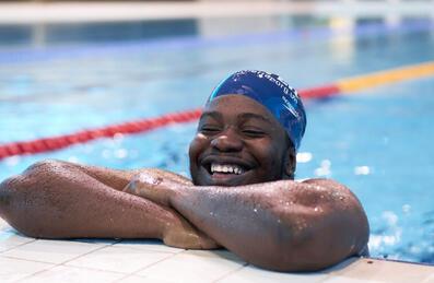 A swimmer hangs off the side of London Aquatics Centre smiling