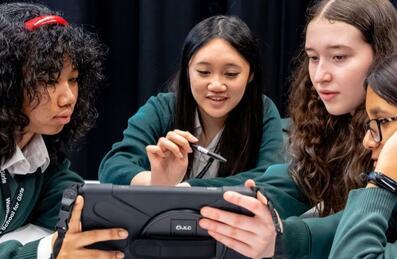 Young people gather round an ipad