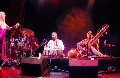 A band with a sitar player in the front play on a stage