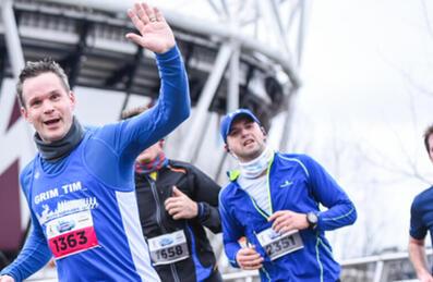 A group of runners smiling to camera with London Stadium in background