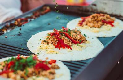 Mexican street food wraps being cooked on a grill outside