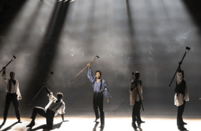 Performers on stage raise their hands aloft