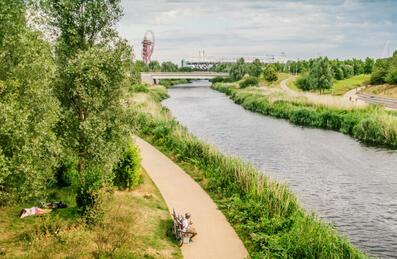 people sat by the river with ArcelorMittal Orbit in the background