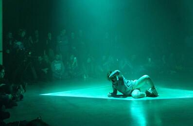 A dancer on stage with a light shining down on them